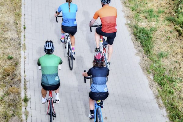 Vier Radfahrer*innen radeln in bunten BasicForm Trikots von DOWE Sportswear