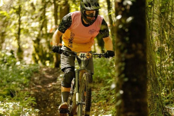 Mountainbiker fährt im Wald und trägt dabei einen Gravity Jersey von DOWE Sportswear in orange-schwarz.