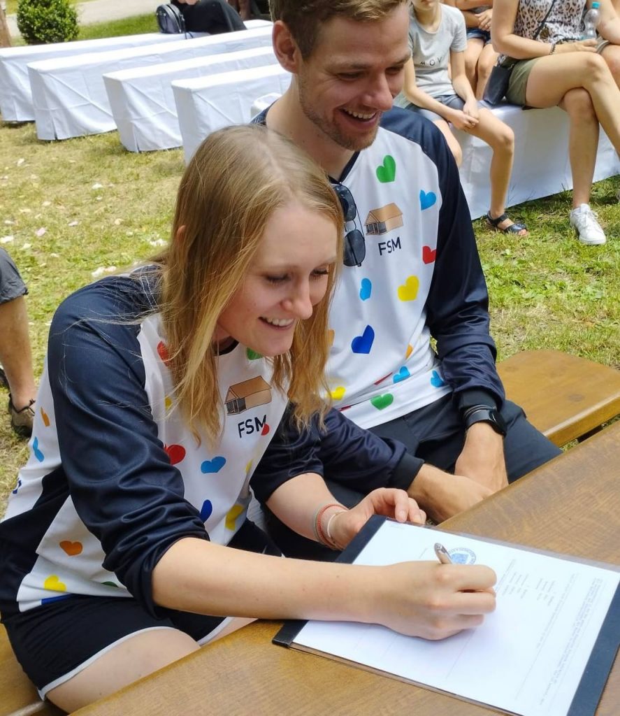 hochzeits-bike-jersey-dowe-sportswear Brautpaar beim unterzeichnen eines Dokuments - Beide tragen langärmlige Bike Jerseys.